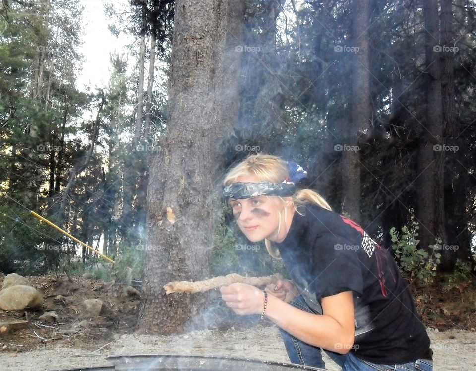 Woman playing toy shooting game with brunches on a camping time