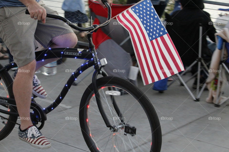 American flag. A Man flying the American flag on a bicycle.