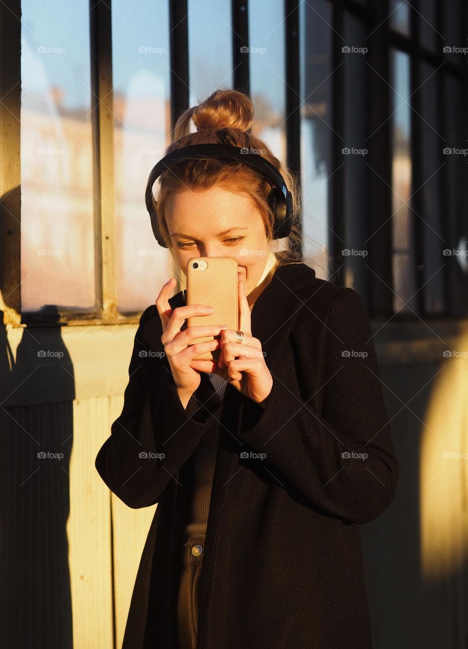 Young beautiful blonde girl with headphones taking photo in the sunny day, portrait of girl 