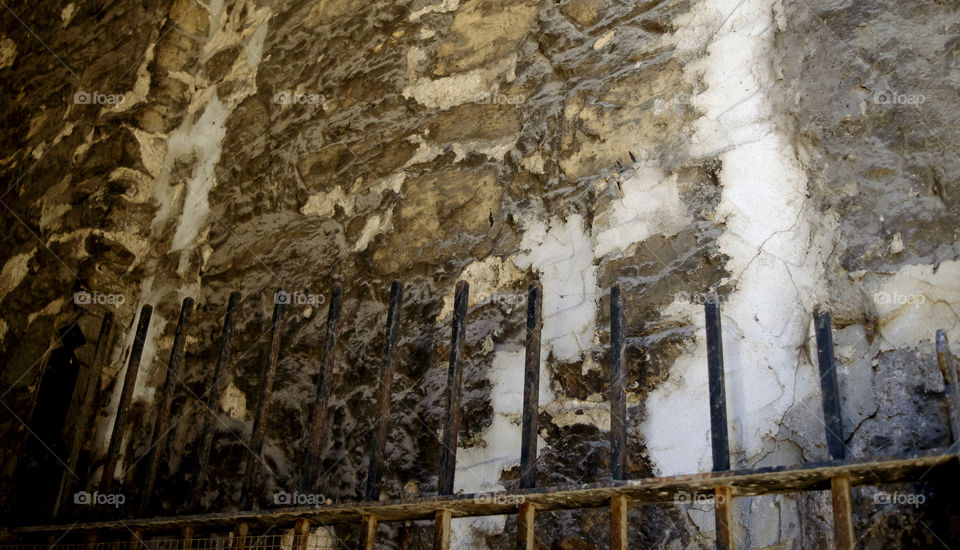 Old stone wall weathered over time in back of ancient wrought iron fence texture in old architecture 