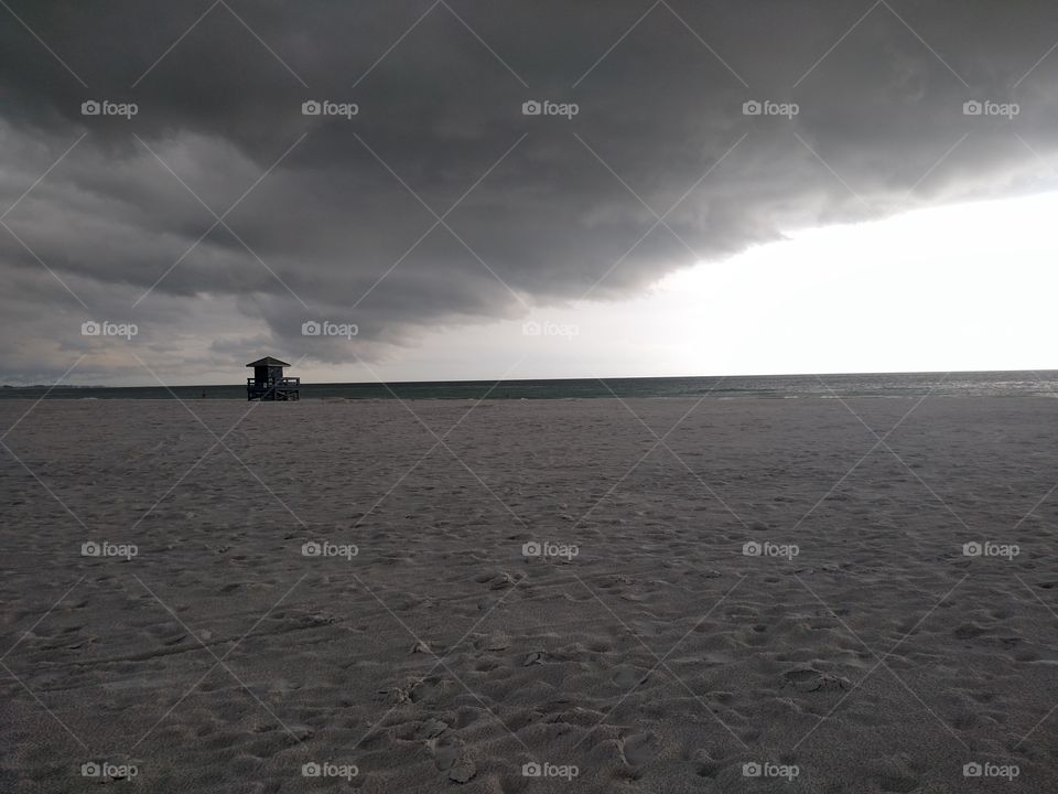 Looming clouds over ocean shore and lifeguard building.