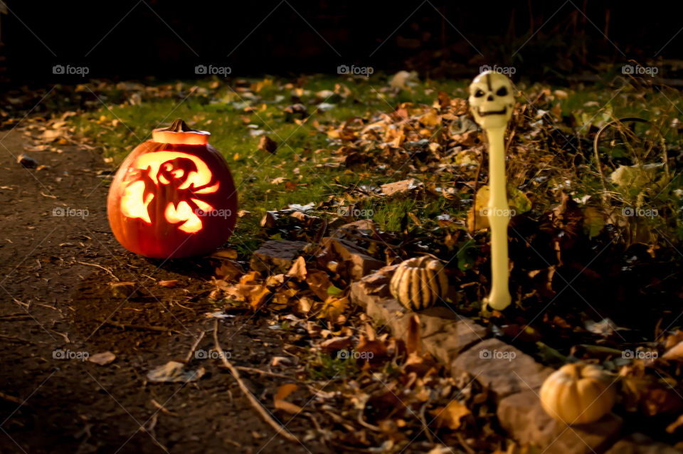 Cute fun jack o’lantern on front lawn with Halloween decorations to invite trick or treaters home on Halloween night creative and inviting on driveway with autumn leaves 