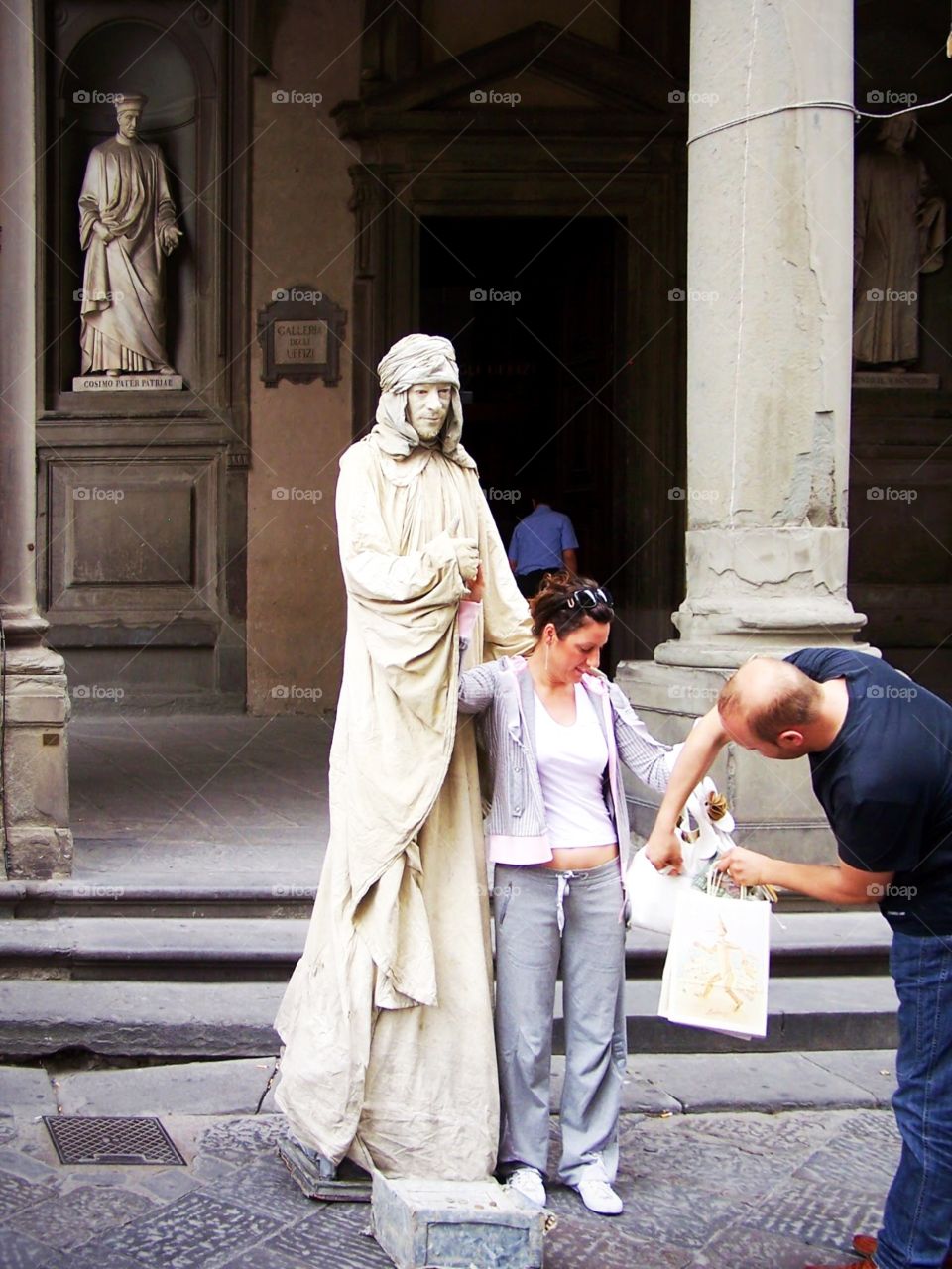 Tourists pose with “live” sculptures covered with chalk under loggia of uffizi 