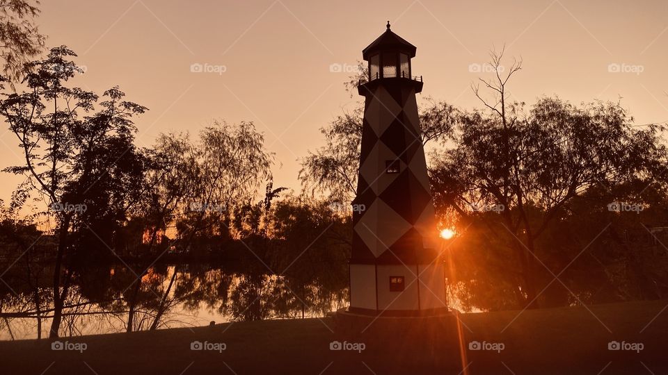 Sunset Lighthouse at Sunset. Sun piercing through landscape giving last bit of scenery light before Sundown. 