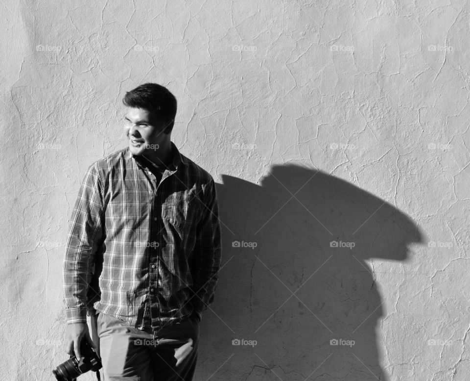 Young photographer standing against wall