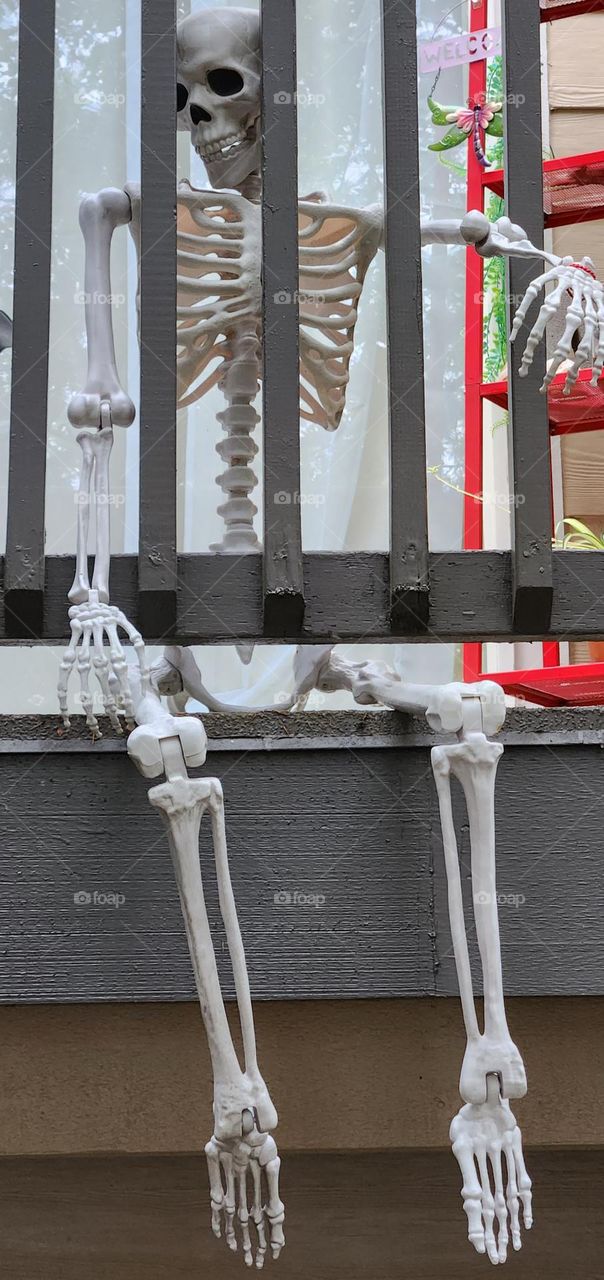 view of a suburban home deck in Oregon decorated for Halloween with a large plastic skeleton