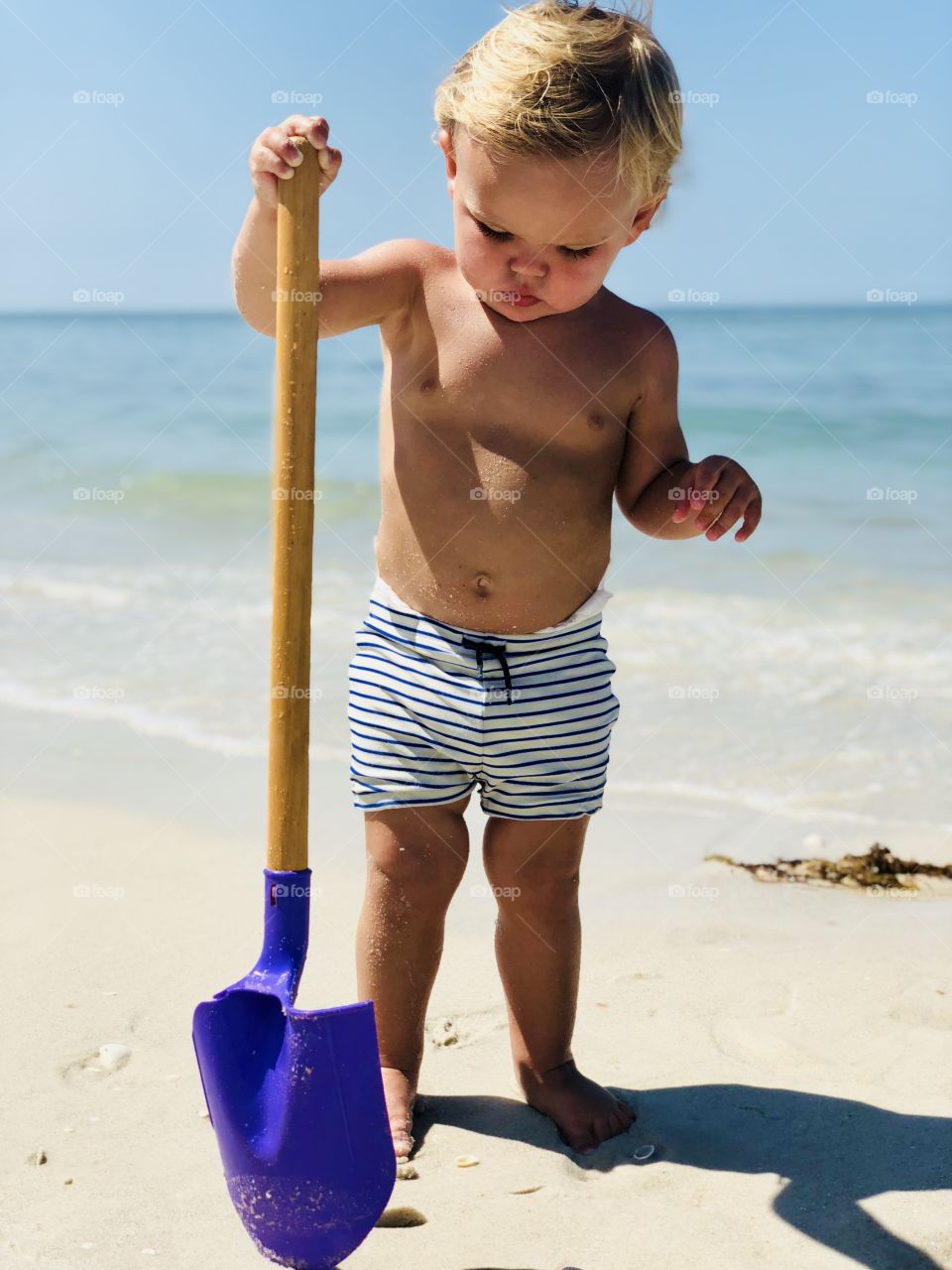 Small child shoveling at the beach 