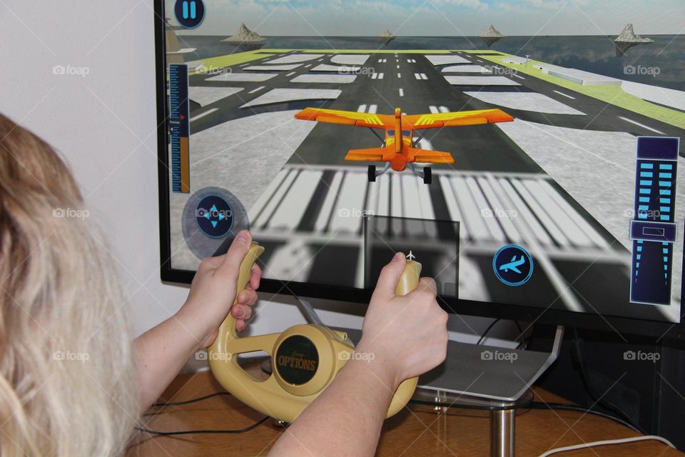 Young woman using flight yoke to play flight simulator at landing