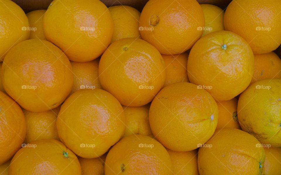 A pile of arranged oranges for sale at an outside market,