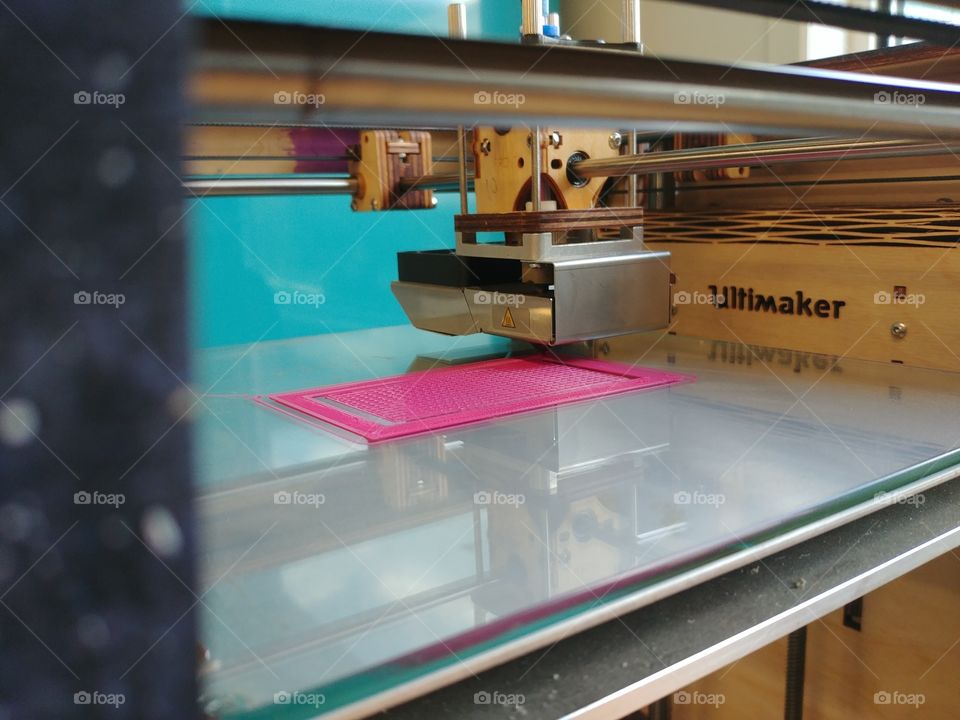 A 3D printer printing out something on an Ultimaker using pink filament.