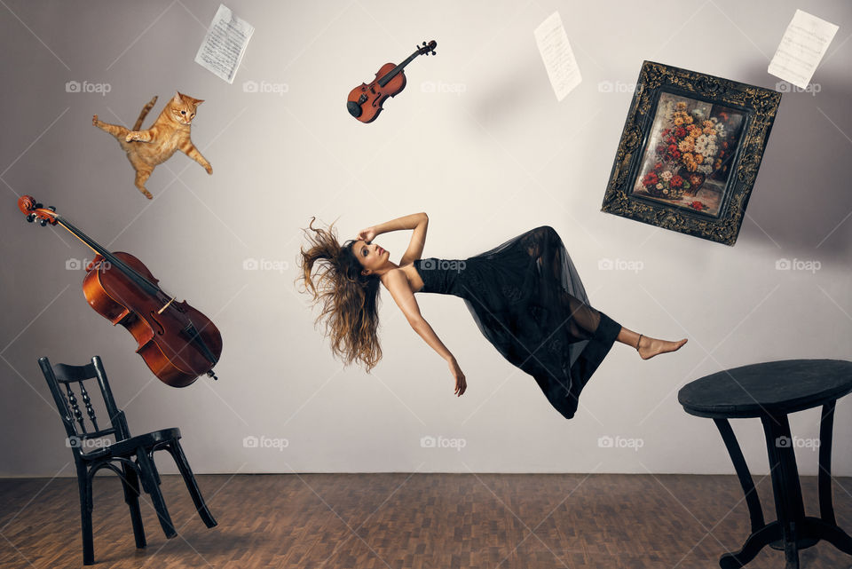 Violin, cat and woman flying in air inside the room