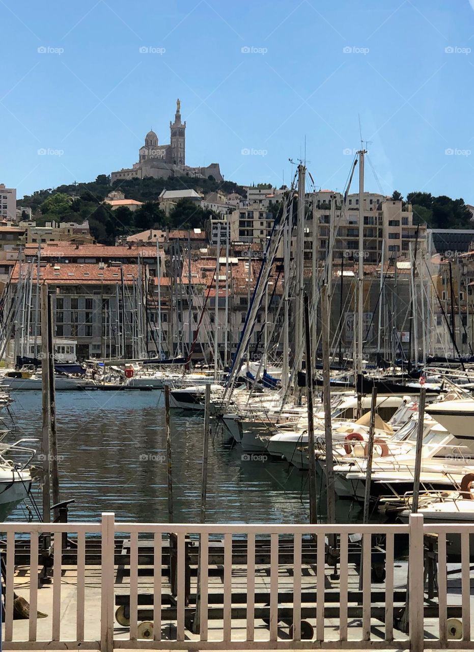 City harbour area with plenty of boats and high cathedral tower on the background 