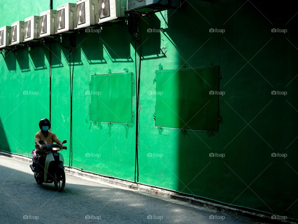 A motorist riding against a green wall back alley