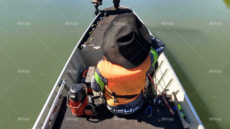 Um pescador. Homem com chapéu dentro do barco.