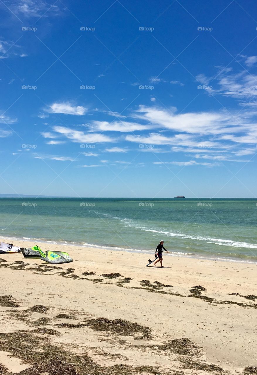 One person walking along remote secluded beach and shoreline on summer day wispy clouds towel on beach south Australia 