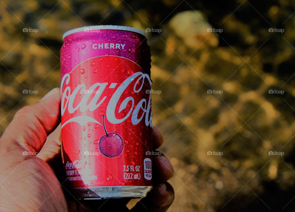 hand holding a refreshing Coca-Cola soda after a nature hike