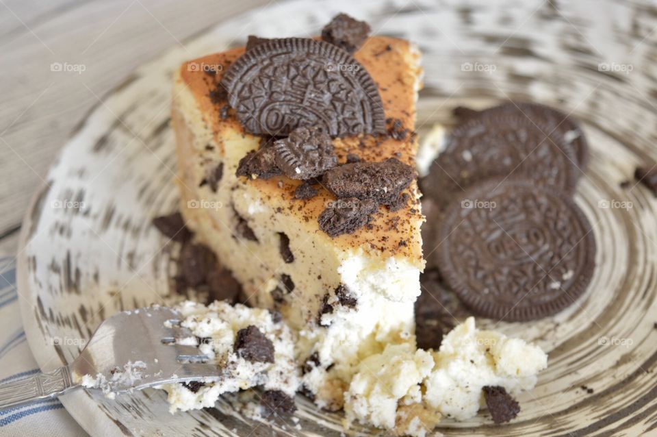 Oreo cookie cheesecake with Oreo cookies and a fork on a high contrasting plate