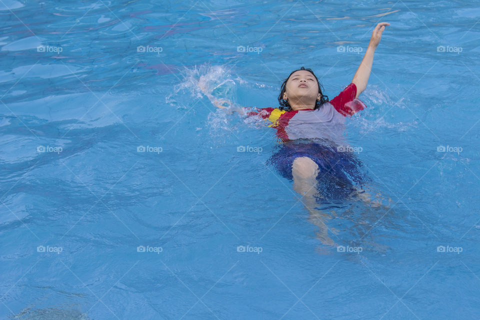 anak kecil yang sedang asyik berenang di kolam renang. terlihat rileks dan menikmati setiap sentuhan air.