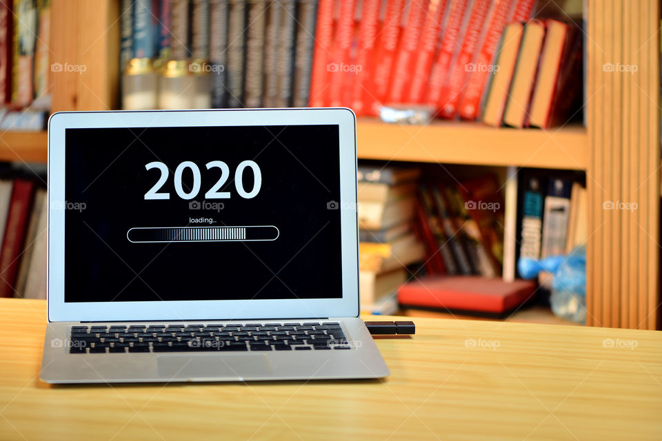 Text - 2020 loading and loading bar on laptop desktop, bookshelf, new year concept