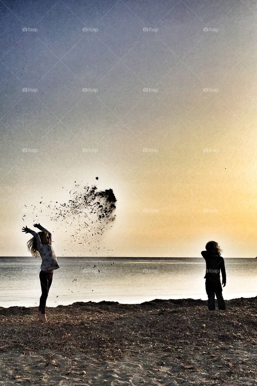 Kids throwing seaweed on the beach