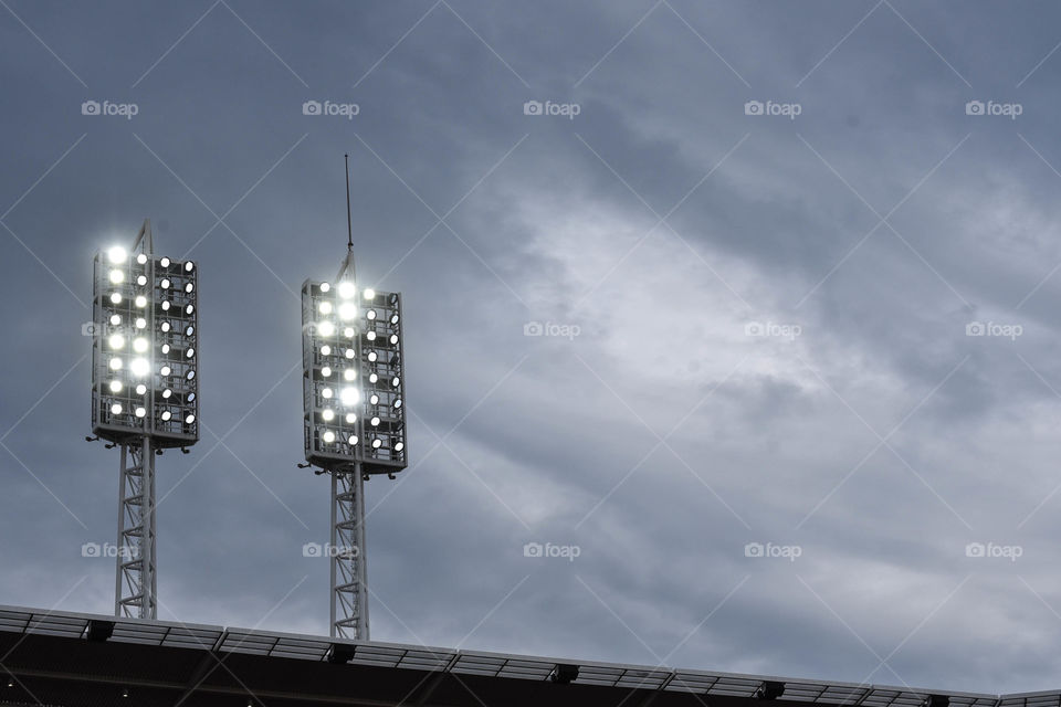 Double stadium lights at dusk illuminating a baseball field 