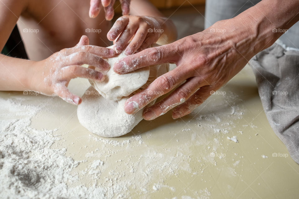 Adult and kids hands making dough for pastry together