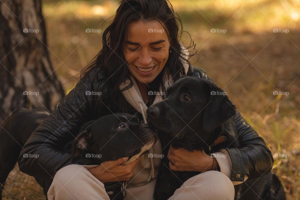 happy owner of two black dogs, friends play in the park, fresh air, sunshine