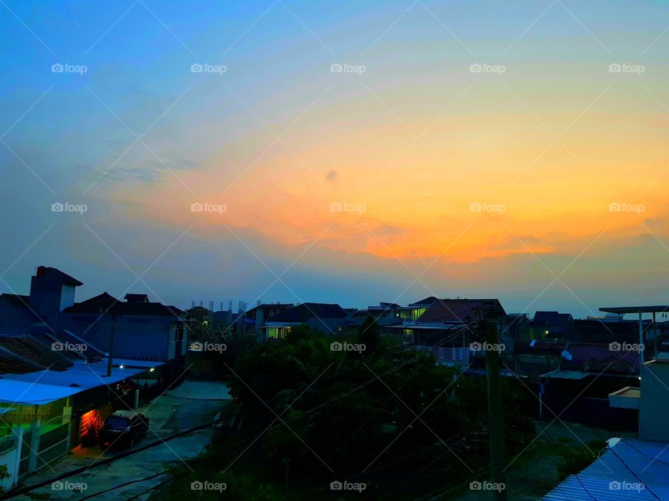 Early morning view, the sky is full of clouds, the sky before sunrise, the sky looks b lue and the clouds reflect a red yellow color, the atmosphere still looks dark, the air in environment feelscold