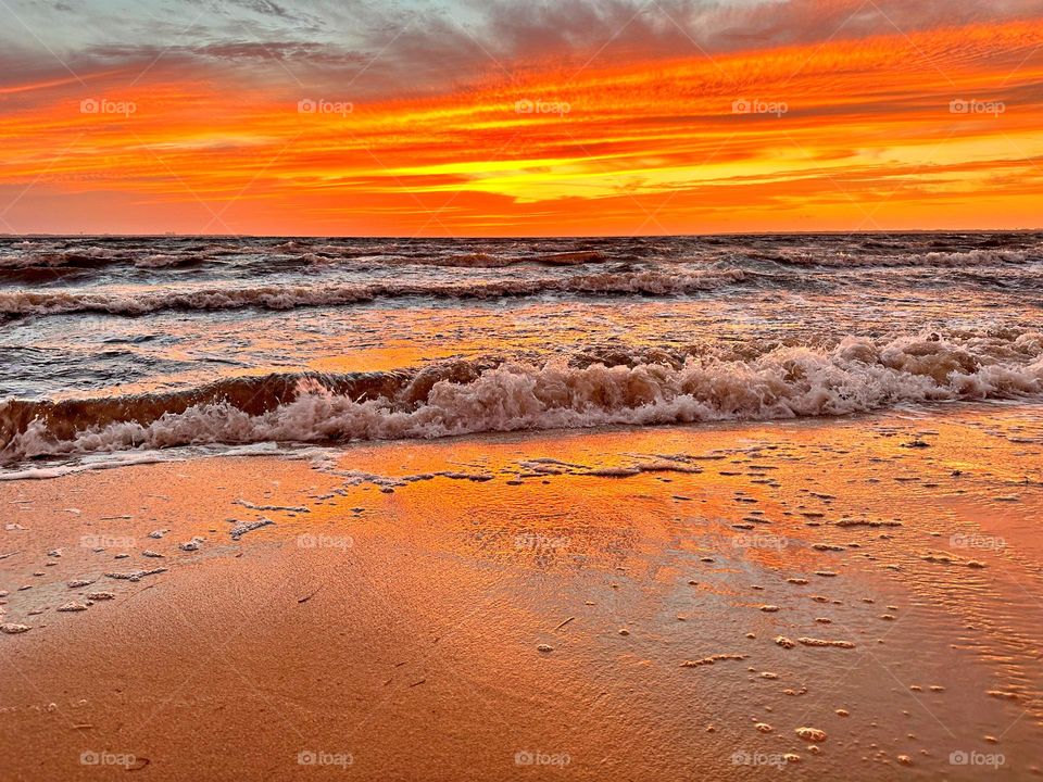 A breathtaking and radiant sunset which colors the waves iridescent, often towers and collides the shore with great force. The impact of the waves against the coastline created a stunning display of energy and motion