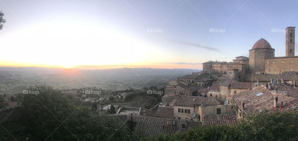 Beautiful view of the grassy hills and part of Volterra with sunset in the background