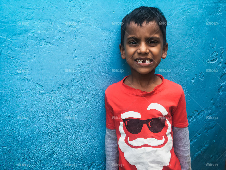 Boy staring in front of a bright blue wall