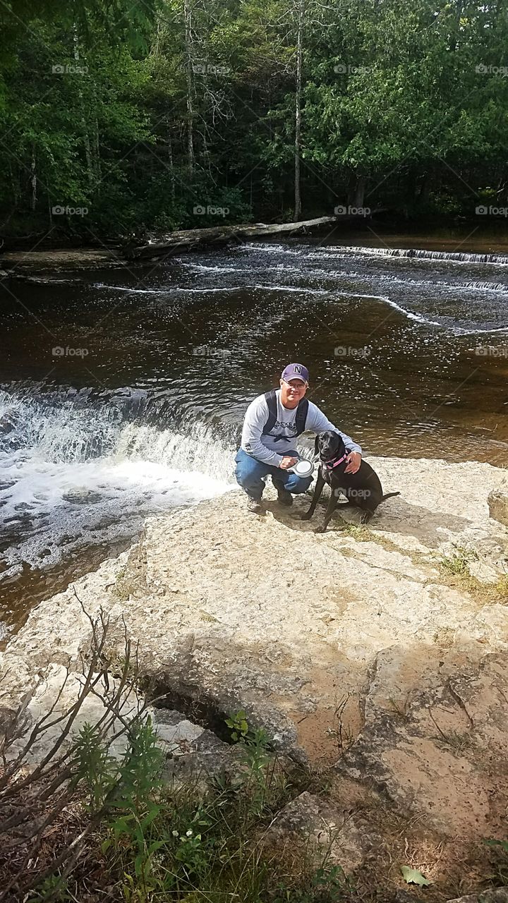 guy with his dog by Rapid River Falls in Michigan upper Peninsula