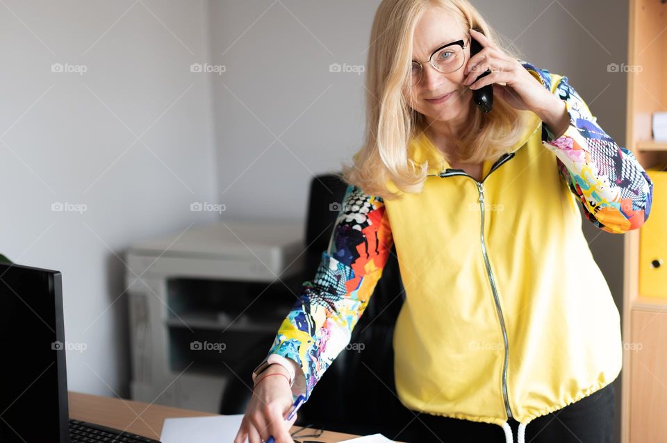 Smiling woman talking on the phone at workplace