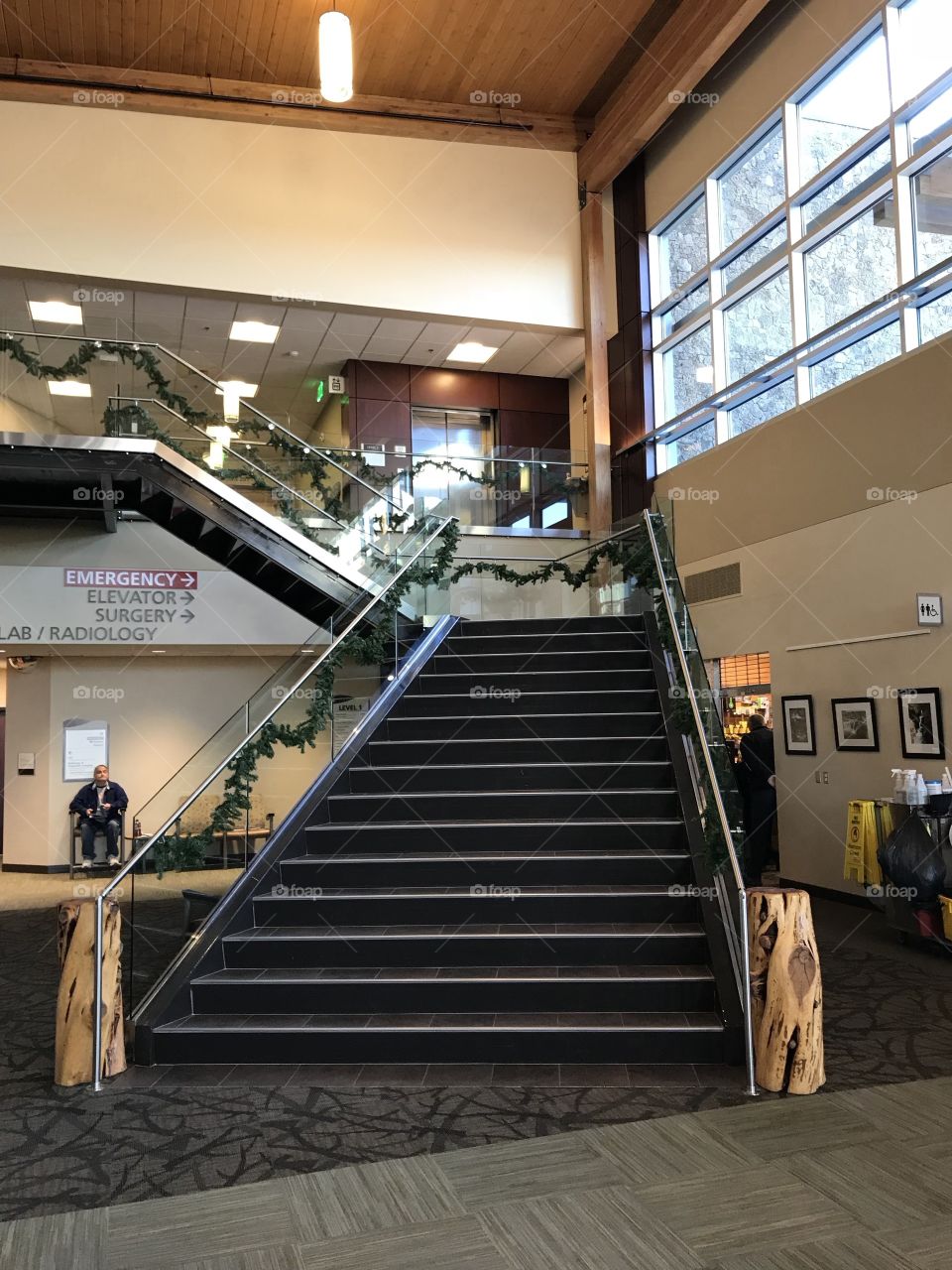 Two levels of stairs decorated with garland for the holiday season lead to an upper floor of a building. 