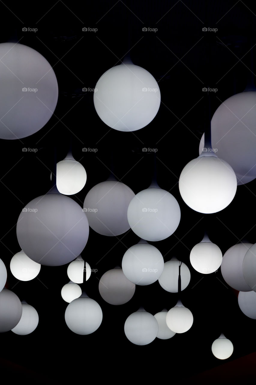 White round lamps hanging from the ceiling, black background 