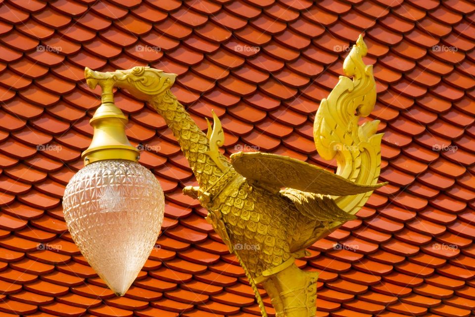 Golden dragon street light. Golden colored dragon street light against red roof tiles. Dragon spread it's wings. Frame filled with roof tiles