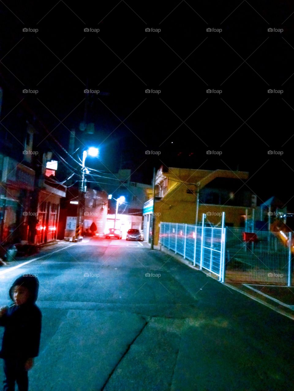 The Road to our way home at night in tongdosa south korea with the little boy that's standing in the middle of the road.