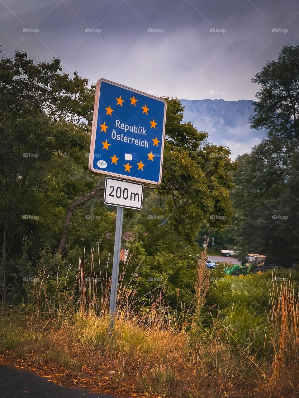 An Austrian EU border signpost, with the mountains and greenery in the background.