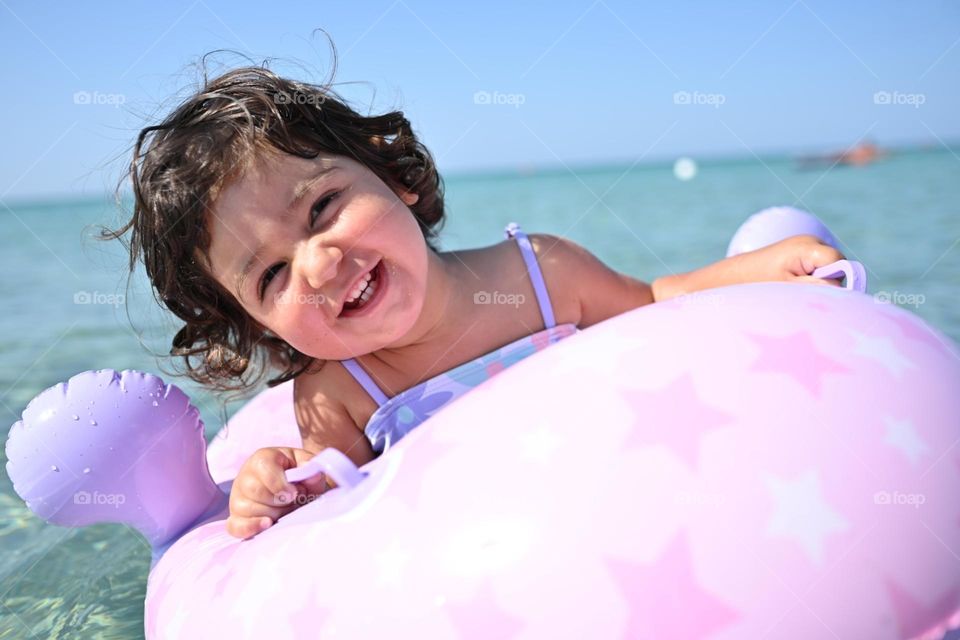 little girl in lilac life jacket having fun at sea
