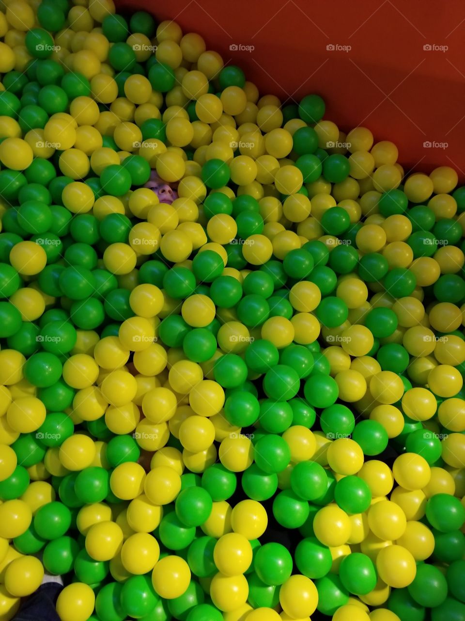 Green and yellow ball pit with a hidden face
