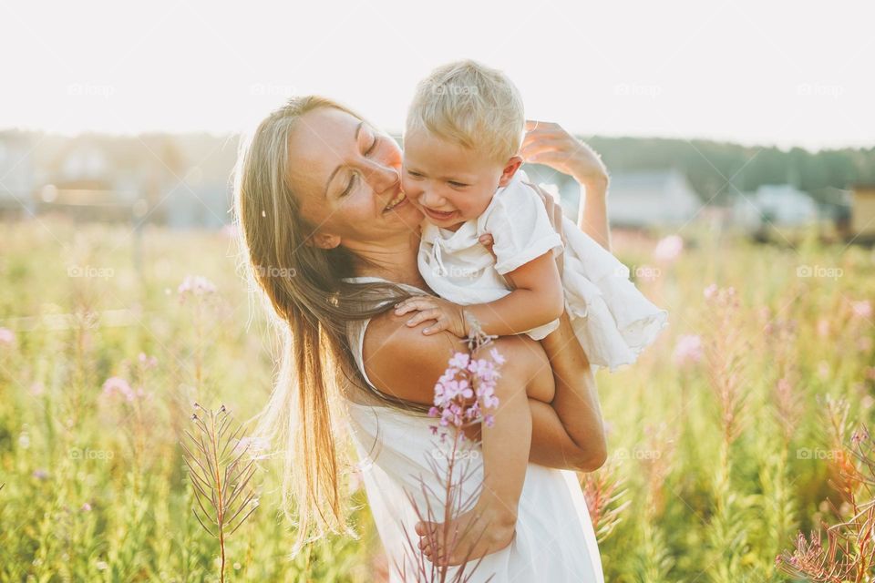 Young woman mother with little girl baby in field on sunset 