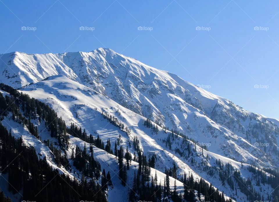 A beautiful scenery of a snowy mountain with a clear sky.