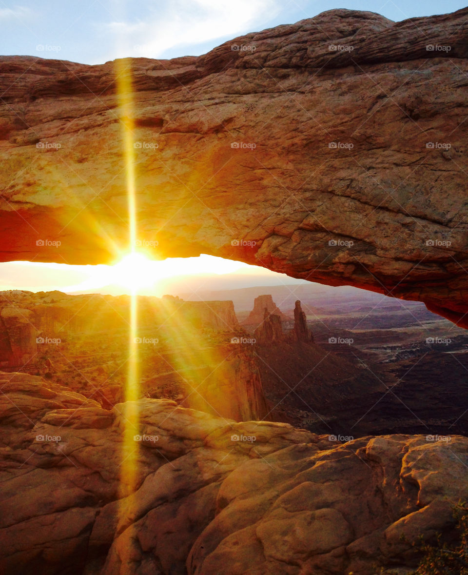 Sunrise Through Canyon Arch. The sun is rising in early morning, bathing the canyon and this arch in its light  