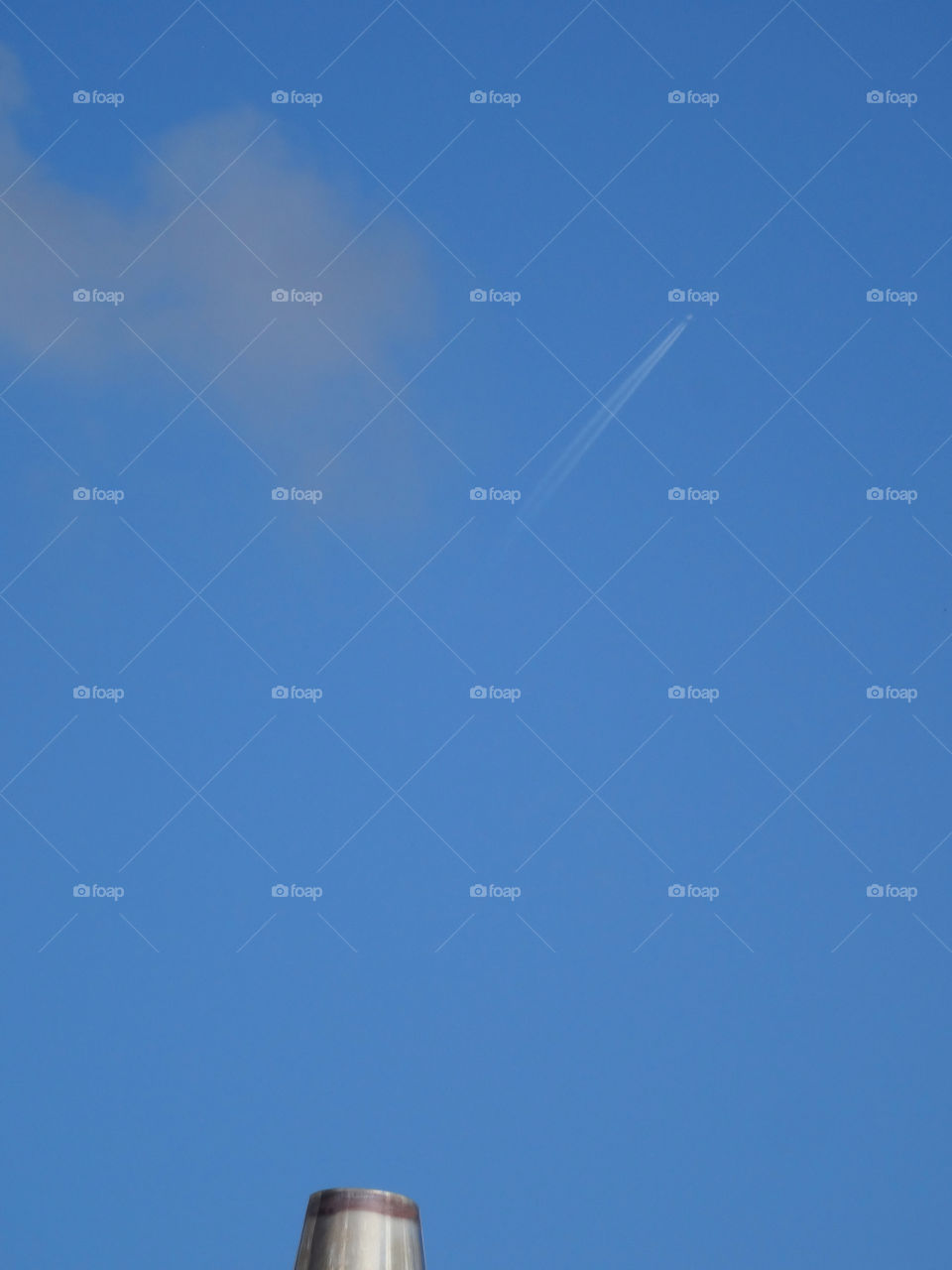 Diffuse vapor trail and blue sky metallic high temperature chimney shooted from low angle view