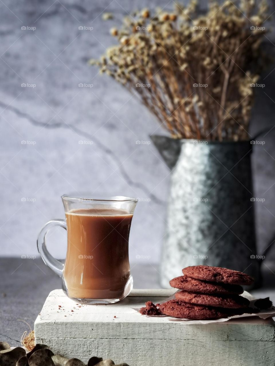 A cup of milky coffee and some chocolate biscuits in close up view