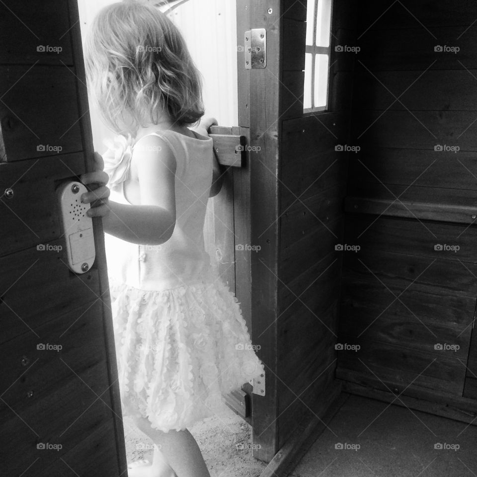 Little girl standing in a wooden playhouse on Easter Sunday. Little lady of the house.