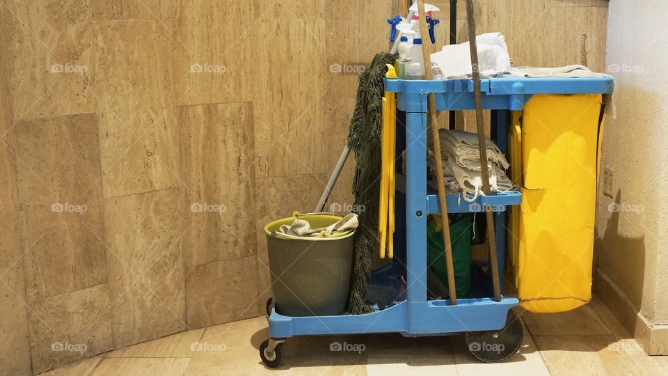 A yellow plastic janitorial cart with cleaning supplies and tools.