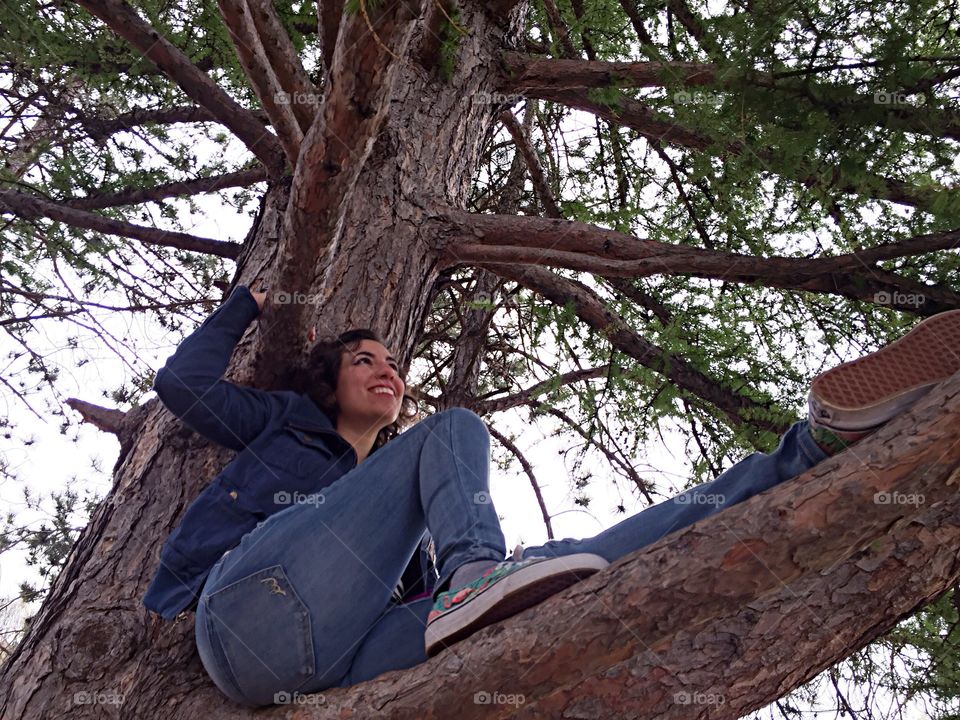 Smiling woman sitting on tree branch