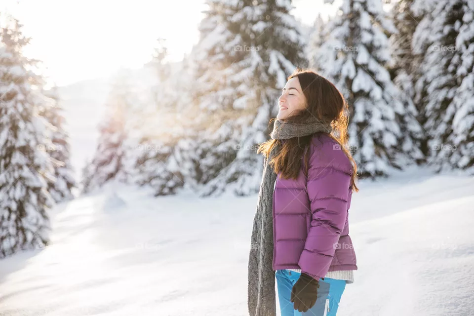 Young millennial woman being joyfull while hiking in a winter landscape at sunset.