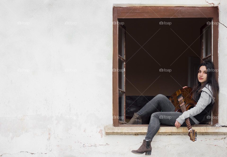 A woman and her guitar on the window